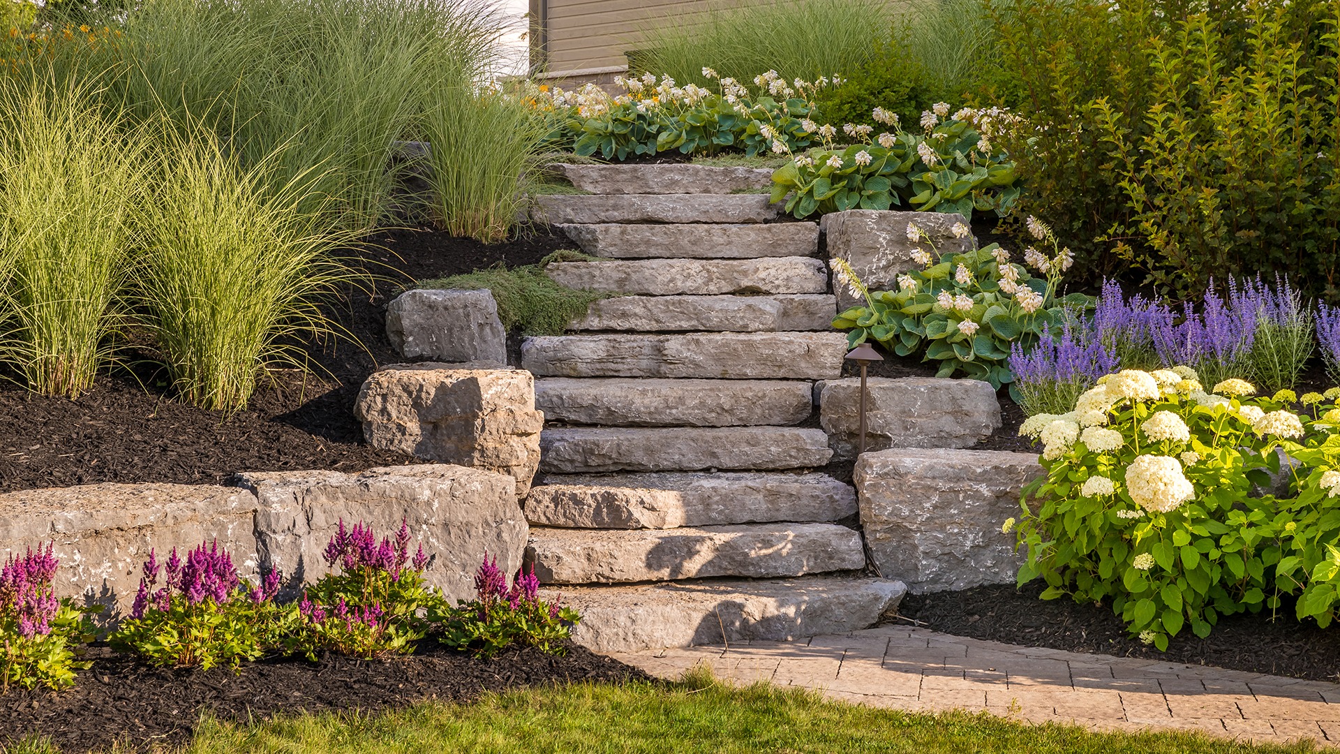 A stone staircase is surrounded by lush greenery and vibrant flowers, creating a charming and serene garden atmosphere.