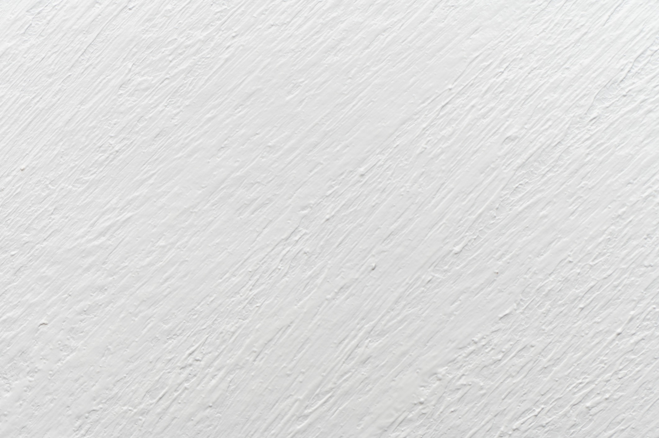 A close-up of a textured white wall surface, displaying diagonal brush strokes and a simple, minimalist design. No landmarks or people visible.